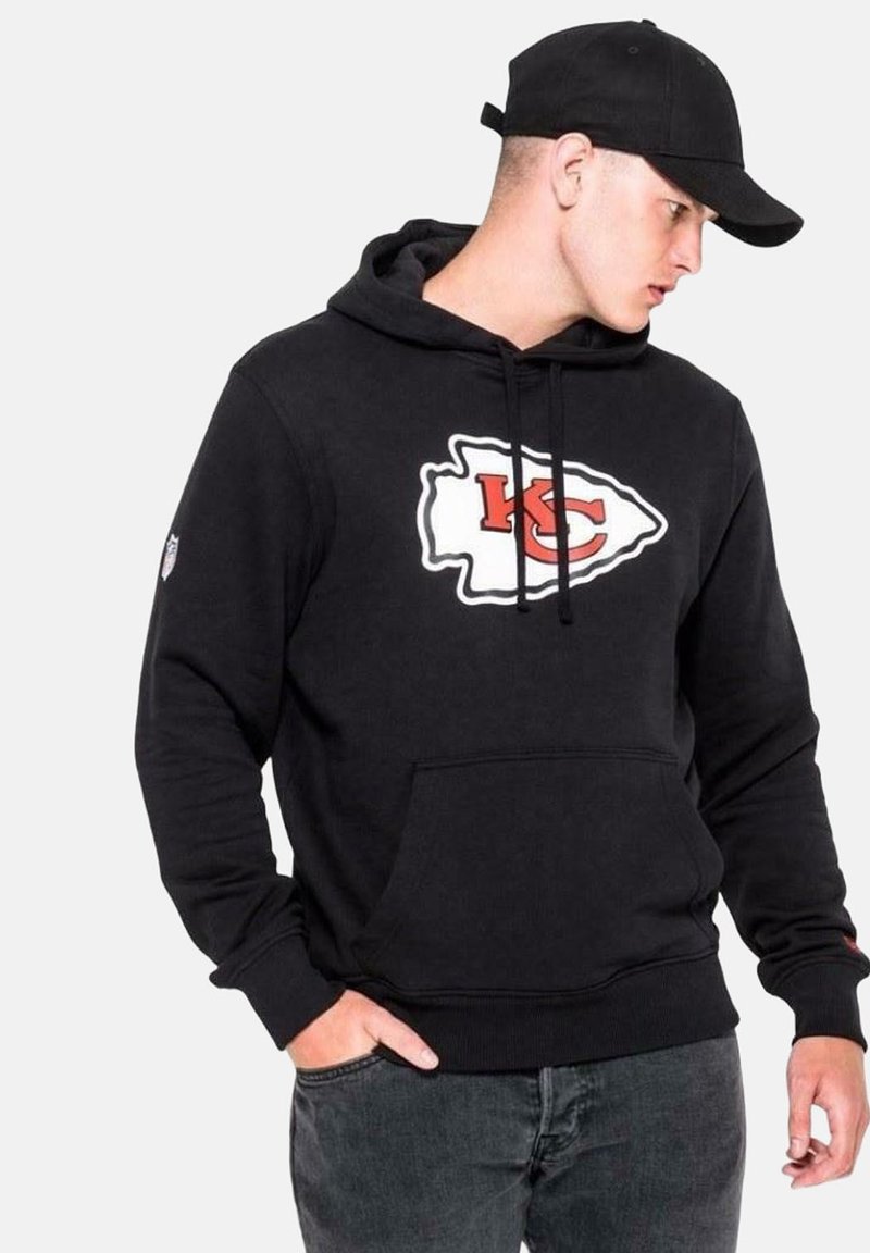 Felpa nera in misto cotone con tasca a canguro frontale, caratterizzata da un grande logo bianco e rosso di Kansas City. Accompagnata da un berretto nero.