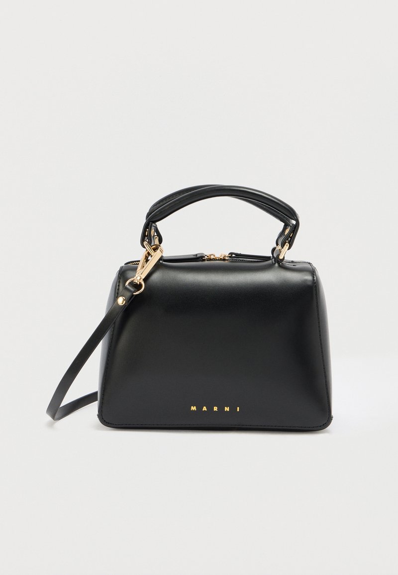 Černá kabelka z kůže s pevnou konstrukcí, horním uchycením, odnímatelným ramenním popruhem a zlatým logem na přední straně.