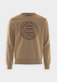 Sudadera marrón hecha de mezcla de algodón. Presenta un gráfico redondo con texto en marrón oscuro, cuello, puños y dobladillo acanalados.