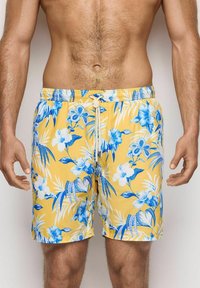 Shorts da bagno gialli con motivo floreale blu, cintura elastica con cordoncino e tessuto leggero.