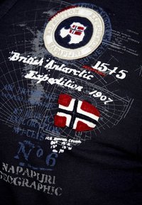 Dunkelblauer Stoff mit bestickten Patches, einschließlich einer Polarkarte und einer norwegischen Flagge in rot, weiß und schwarzen Akzenten, mit Textdetails.