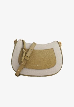 Petit sac bandoulière en tissu beige avec poche avant en cuir vert olive, sangle réglable, accessoires dorés et fermeture éclair.