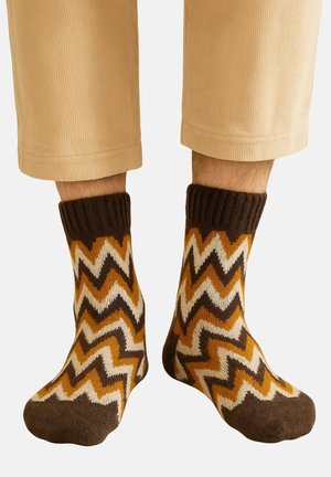 Kniestrümpfe aus weichem Material mit Zickzackmuster in Braun, Senfgelb und Creme, mit dunklem, geripptem Bündchen.