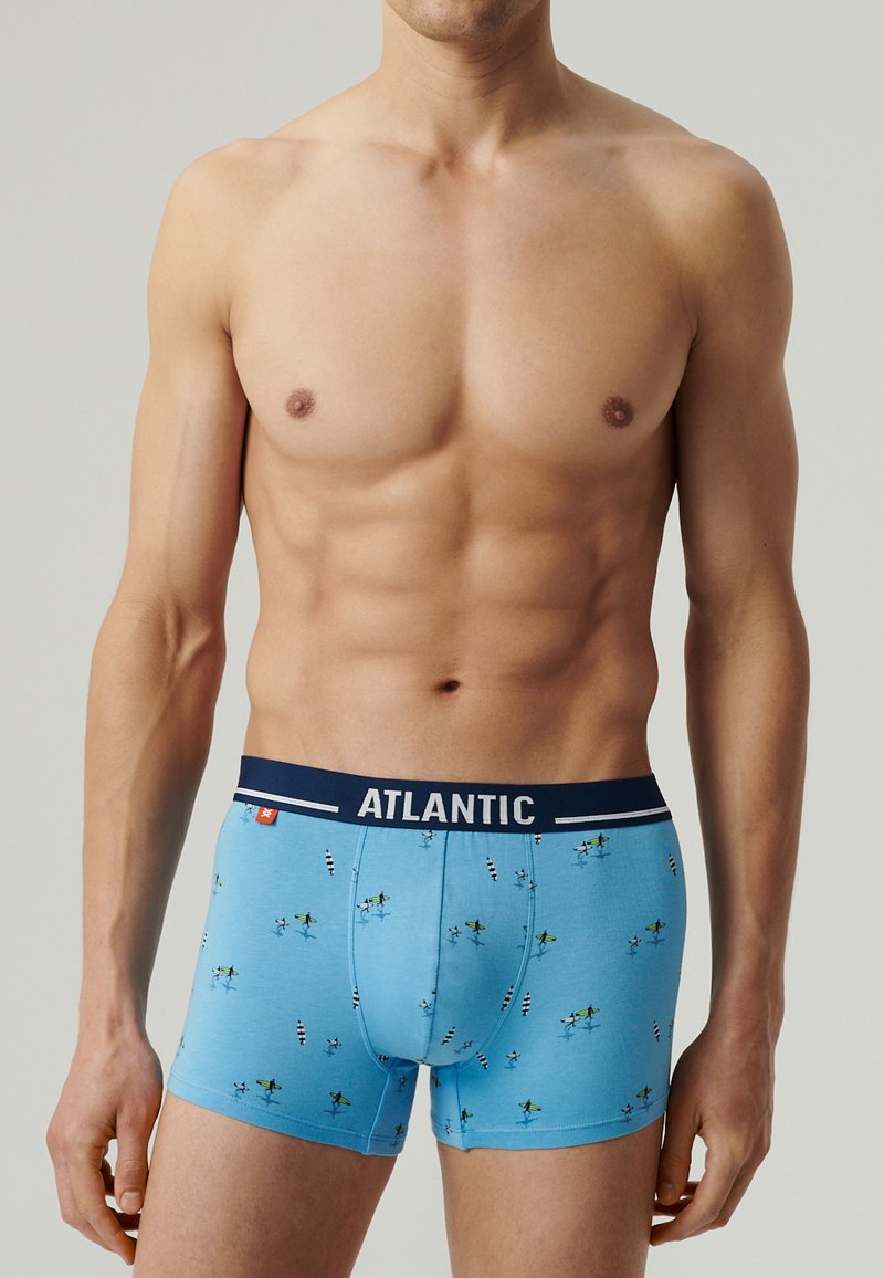 Niebieskie slipki bokserskie z granatowym paskiem z napisem "ATLANTIC." Materiał zdobiony wzorem kolorowych desek surfingowych i palm.