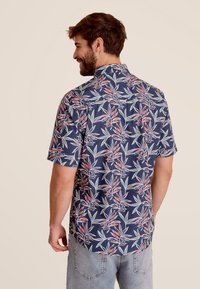 Korte mouw shirt in marineblauw met een bloemenpatroon van groene en rode bladeren; lichte stof, op maat gemaakte kraag en eenRelaxed fit.