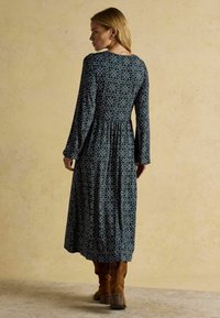 Langärmliges, dunkelblaues Kleid mit floralem Muster in Creme, mit einem taillierten Oberteil und geraffter Taille, das bis zur Wade reicht.