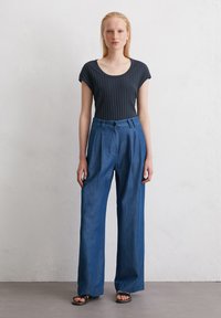 Dark ribbed short-sleeve top with a scoop neckline; loose, light-blue wide-leg trousers with front pleats and a button closure.