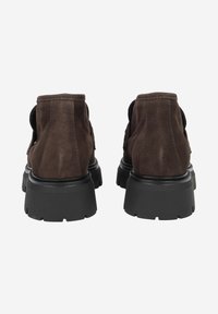 Brown suede shoes with a thick black rubber sole, featuring a rounded design and visible stitching on the upper.