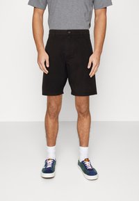 Černé šortky se rovnými nohavicemi, bavlněný materiál, boční kapsy a poutko na pásek. Kombinované se šedým tričkem a vícebarevnými teniskami.