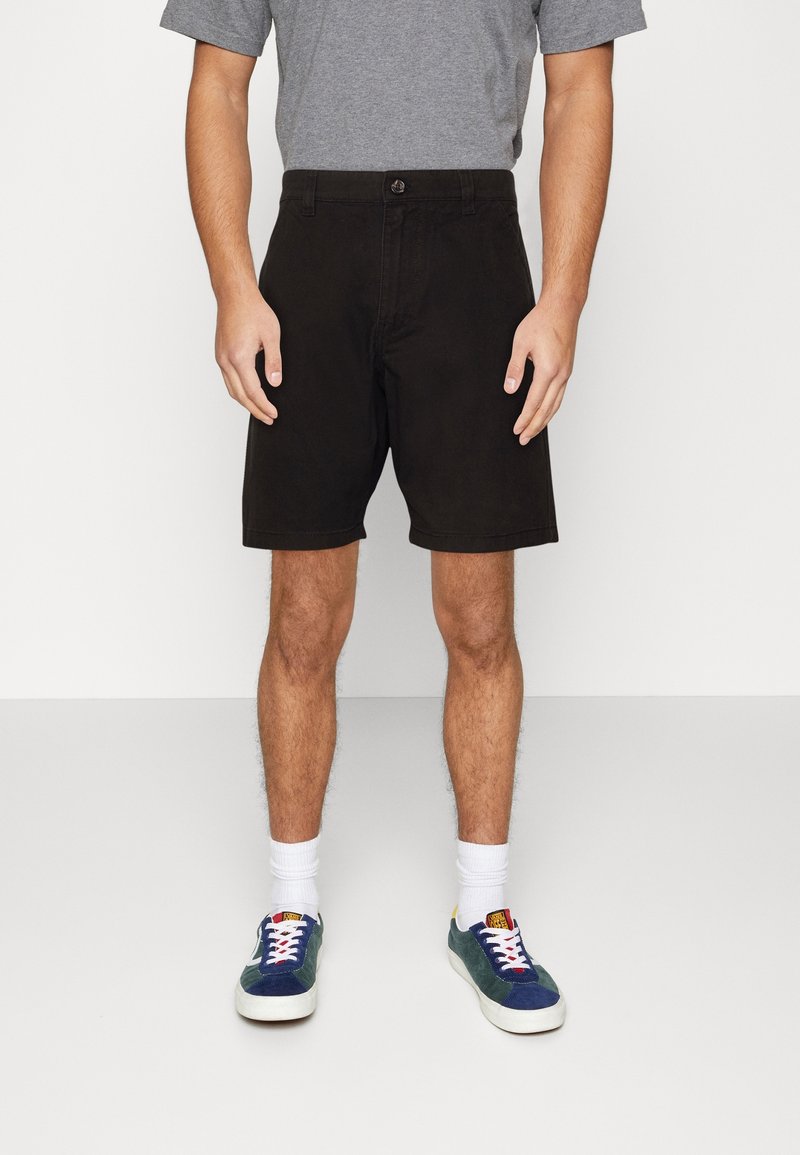 Černé šortky se rovnými nohavicemi, bavlněný materiál, boční kapsy a poutko na pásek. Kombinované se šedým tričkem a vícebarevnými teniskami.