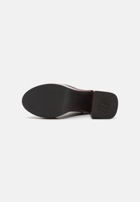 Zapato de tacón de cuero burdeos con acabado texturizado, puntera redonda y suela de goma negra sólida con un sutil acento de logo.