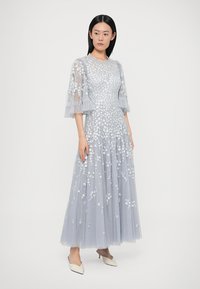 Jasnoniebieska sukienka z tiulu z kwiatowym haftem, krótkimi falbanianymi rękawami i zwiewną spódnicą. Szczegółowe wykonanie i delikatna faktura.