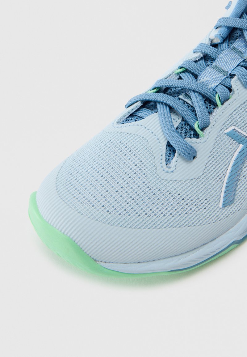 Hellblauer Sportschuh mit strukturiertem Mesh-Obermaterial, kontrastierender grüner Außensohle und abgerundeter Spitze. Verfügt über robuste Schnürsenkel und dezentes Logodetail.