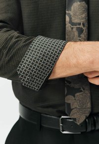 Czarna koszula w wzory z kontrastującym wytłoczonym mankietem i ciemnym kwiatowym krawatem. Charakteryzuje się gładką teksturą i dopasowanym krojem.