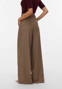 Pantalones de pierna ancha marrones con cintura alta, que cuentan con bolsillos traseros y una textura de tela suave. Diseño minimalista con líneas limpias.