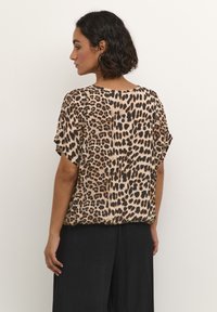 Animal print blouse featuring a loose-fitting design, short sleeves, and a rounded neckline. Fabric appears lightweight with a silky texture.