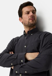 Dunkelblaues Hemd mit Knopfleiste aus weichem Stoff, mit einer Brusttasche, geknöpften Manschetten und einem dezenten Markenlogo auf der Tasche.