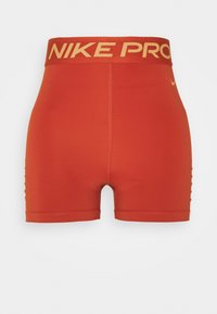Jasně oranžové sportovní šortky Nike Pro s širokým pasem a žlutým logem swoosh na pravém boku, vystavené na bílém pozadí.