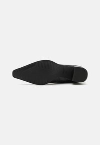 Talpa de pantof din piele neagră, cu o textură netedă și o ușoară curvature. Modelul cu caneluri oferă aderență, având o formă conică spre vârf.