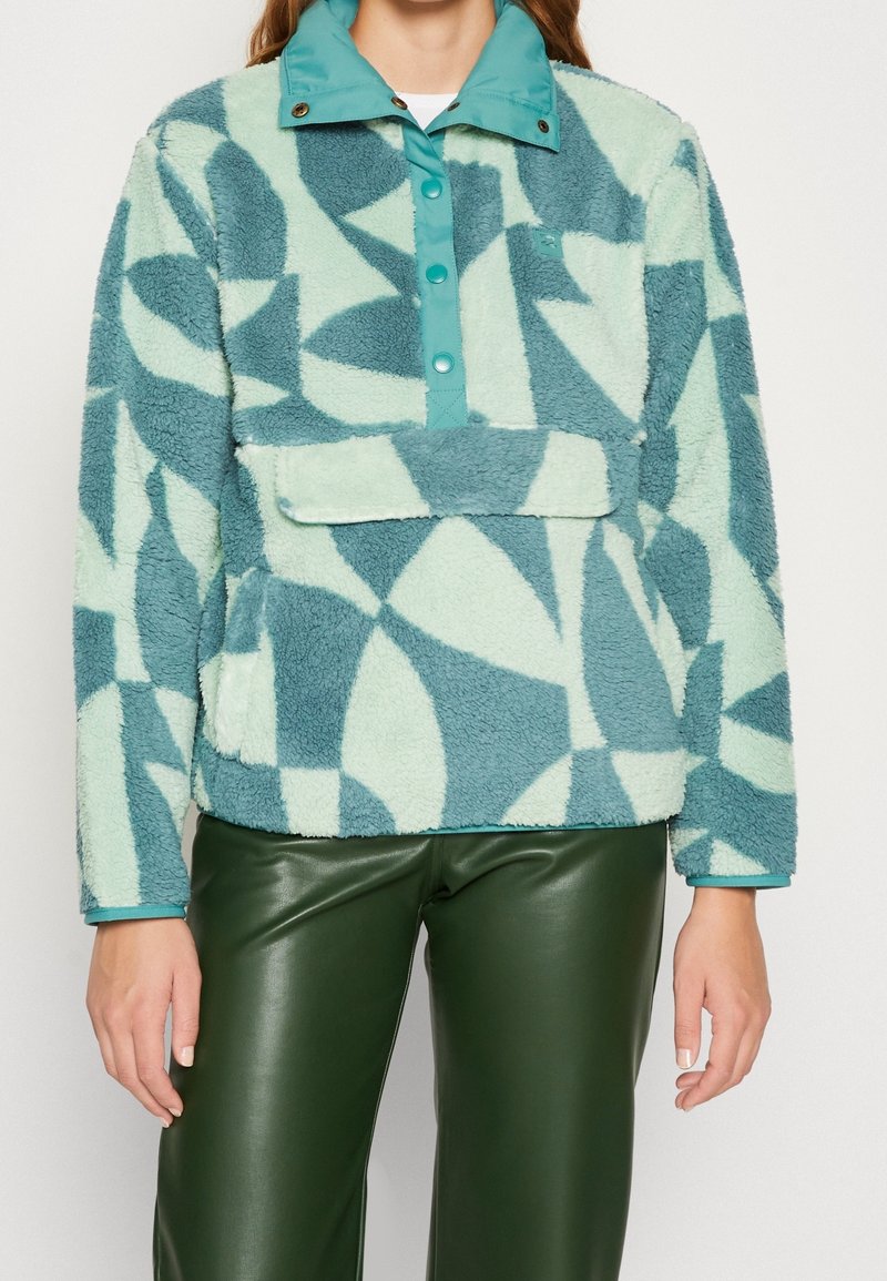 Sudadera de forro polar en verde menta claro y verde azulado con un patrón geométrico, con cuello de botones a presión y bolsillo delantero tipo canguro. Textura suave.