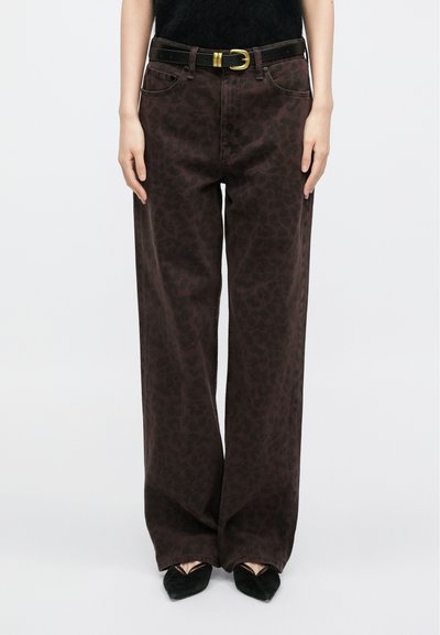 Hnedé džínsové nohavice s širokými nohavicami a jemným leopardím vzorom, skombinované s čiernym opaskom so zlatým kovaním. Hladká bavlnená textúra látky.