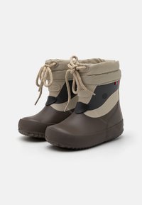 Bottes en caoutchouc marron avec des tiges en textile beige, cordon de serrage ajustable et accents noirs. Semelles texturées pour l'adhérence. Présente un logo sur le côté.