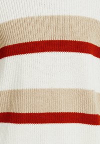 Stickad tröja med horisontella ränder i beige, kräm och kraftigt rött. Strukturerad tyg med avslappnad passform.