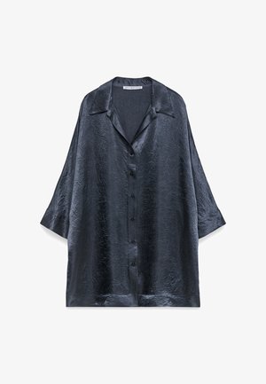 Ciemnoniebieska, teksturowana bluzka o błyszczącym wykończeniu, z zapięciem na guziki z przodu i krótkimi rękawami. Posiada klasyczny kołnierzyk oraz luźny, oversize'owy fason.