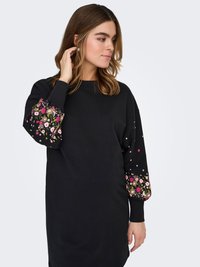 Black sweatshirt dress with long sleeves featuring colorful floral embroidery and patterned accents on both sleeves. Soft fabric texture.