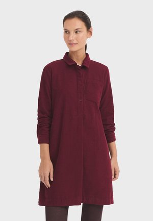 Bordeauxfarbenes Cordhemdkleid mit Kragen, langen Ärmeln und einer Brusttasche. Verfügt über eine Knopfleiste vorne und einen geraden Schnitt.