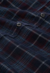 Marineblauwe en bordeaux geruite shirt van katoen met een gestructureerde afwerking, voorzien van twee zwarte knopen en afwisselende horizontale en verticale lijnen.