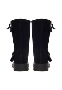 Botas de ante negras hasta la rodilla con punta redonda, dos correas laterales con hebillas y una suela de goma negra lisa. Diseño de tacón plano.