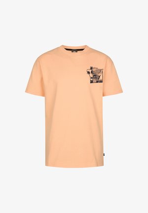 Brzoskwiniowa bawełniana koszulka z graficzną kieszonką, zestawiona z szortami jeansowymi z podwiniętymi mankietami. Dopełnieniem stylizacji są białe trampki i paskowane skarpetki do kostek.