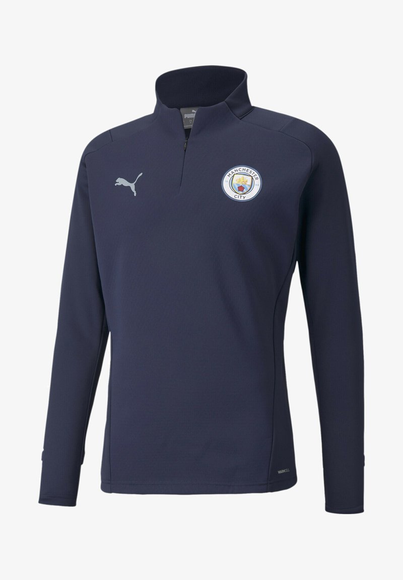 Navyblauer Pullover mit langen Ärmeln, halbem Reißverschluss und hohem Kragen. Mit einem Manchester City-Logo auf der Brust und einem kleinen Puma-Logo auf der Schulter.