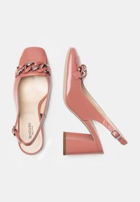 Coral patent slingback heels with a square toe, shiny chain detail across the vamp, and a wooden block heel. Buckle closure on the ankle strap.