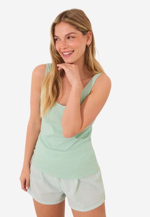 Débardeur côtelé vert clair à larges bretelles associé à un short léger à motifs, avec une coupe décontractée et une texture douce.