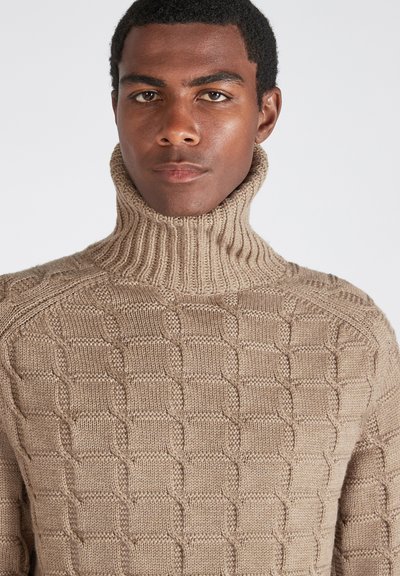 Maglione lavorato a maglia beige con colletto alto a coste, motivi testurizzati e una vestibilità morbida. Il tessuto sembra spesso e ha una finitura morbida.