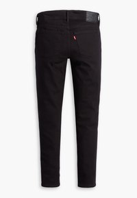 Black, slim-fit jeans with a smooth texture. Features two back pockets, a branded leather patch, and a zipper fly. Clean design.