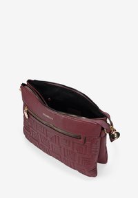 Bolsa de mano de cuero marrón con textura trenzada, que cuenta con dos compartimentos con cremallera, herrajes en tono dorado y logo en relieve en la parte frontal.