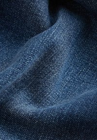 Tela de denim en azul oscuro, con una textura suave y ligeras variaciones en los tonos, además de un clásico patrón de tejido.
