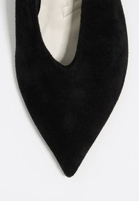 Décolleté nera in suede con punta a punta e profonda apertura ai lati, caratterizzata da una morbida fodera interna e un sottile dettaglio di cucitura lungo i bordi.