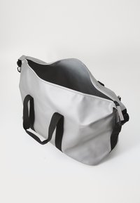 Borsa impermeabile grigia con manici neri, aperta per mostrare il suo interno, su uno sfondo bianco uniforme.