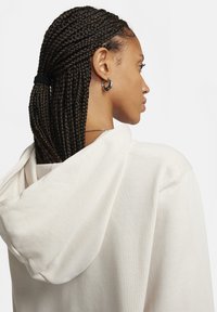 Felpa con cappuccio color beige chiaro con coulisse, tessuto testurizzato e vestibilità rilassata, caratterizzata da una cucitura visibile e un orlo largo.