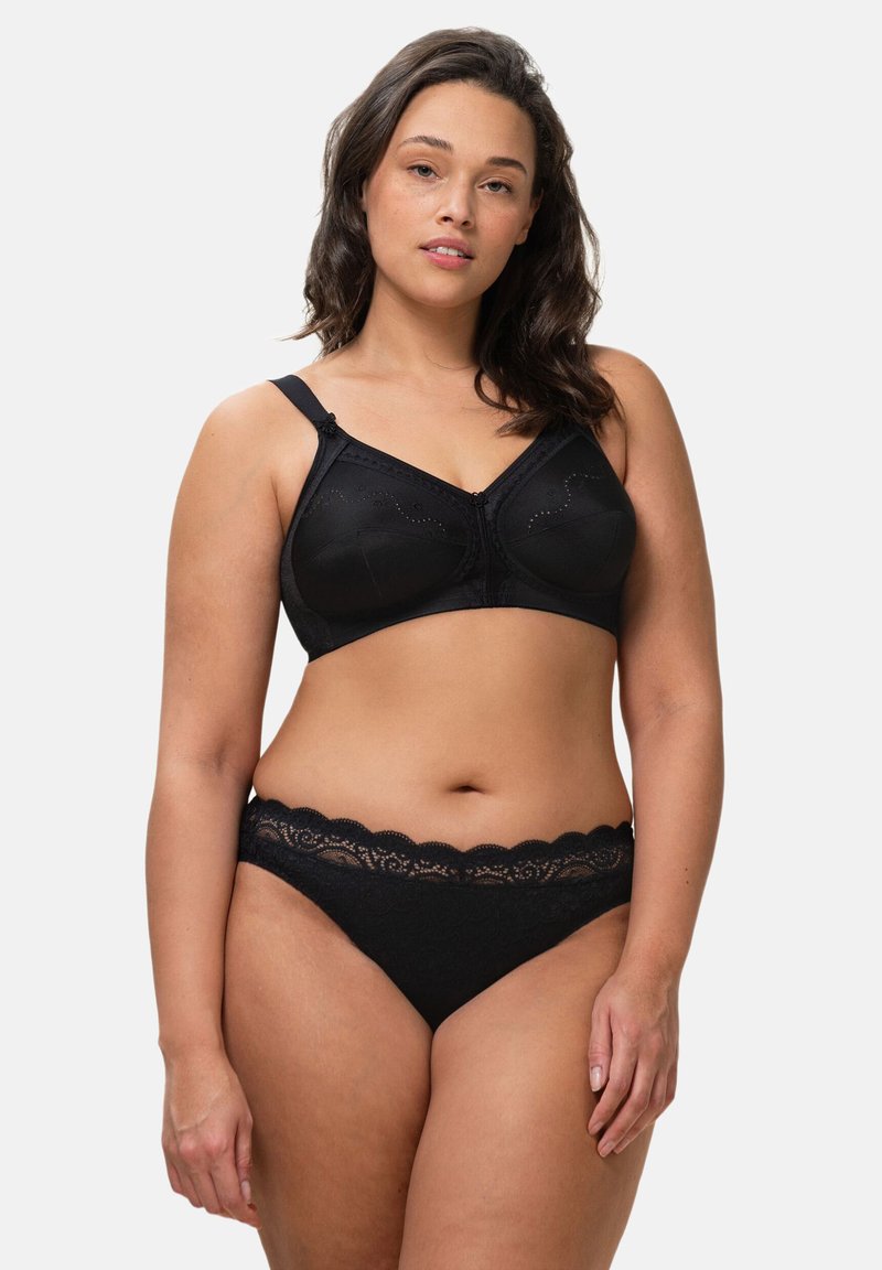 Ensemble de lingerie noire comprenant un soutien-gorge à finition lisse, bretelles ajustables, et des culottes ornées de dentelle avec une ceinture festonnée.