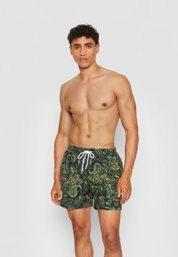 Grüne Badeshorts mit einem gelben und dunkelgrünen Paisley-Muster, ausgestattet mit einem weißen Kordelzug und einem lässigen Schnitt.