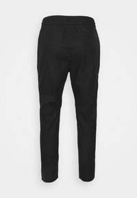 Czarne spodnie z elastycznym pasem, zwężającym się krojem nogawki i jedną kieszenią z tyłu. Materiał wydaje się gładki z delikatnym połyskiem.