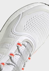 Vitaid träningsskor med texturerat nättyg på ovansidan, gummisula, kompletterade med reflexdetaljer och klargula snöröglor.