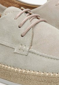 Světlé šedé semišové boty s zaobleným tvarem, se světlými šněrovacími tkaničkami a tkanou jutu podešví. Texturovaný povrch a jemné švy jsou patrné.