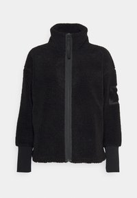 Czarna kurtka polarowa z wysokim kołnierzem, pełnym suwakiem i elastycznymi mankietami. Posiada fakturowaną powierzchnię oraz naszywkę na rękawie.