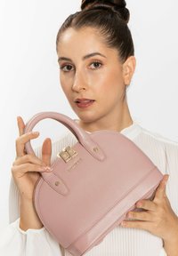 Bolso de mano texturizado en color rosa con forma redondeada, doble asa superior, herrajes en tono dorado y detalle del logo en la parte delantera. Acabado liso y elegante.